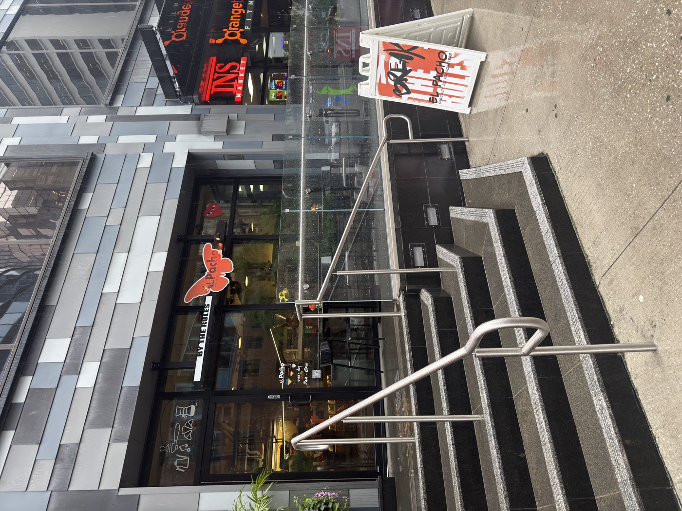 El Pacho Coffee Roasters storefront in downtown Toronto on a rainy day, with wet steps and the orange butterfly logo on the glass